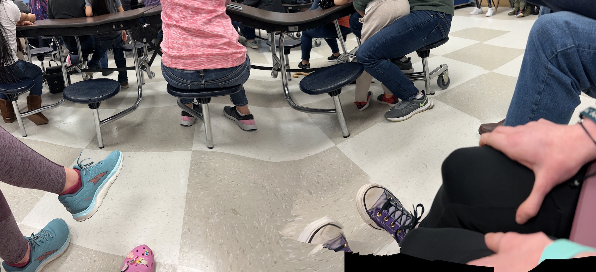 Feet of 4 family members in an elementary cafeteria. 