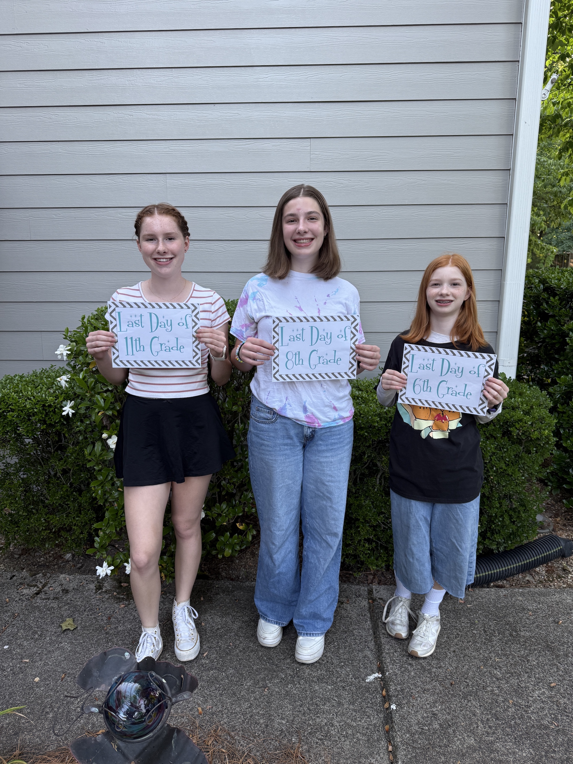 N, E and B on their last day of school with last day of school grade signs